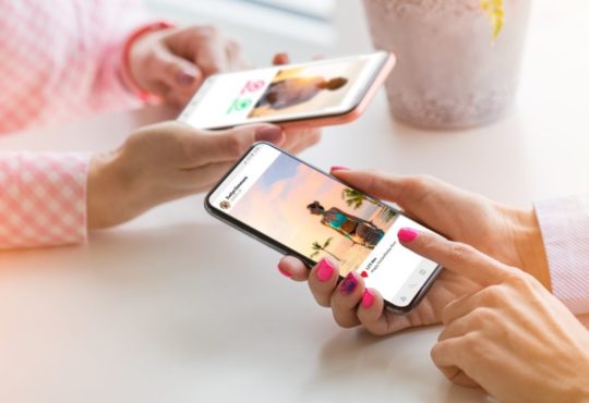 Two women using their mobile phones together