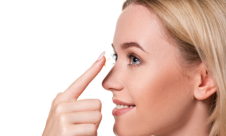 Young woman holding contact lens on index finger with copy space. close up face of healthy beautiful woman about to wear contact lens.