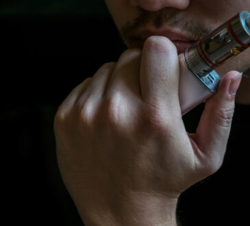 Man with concealed identity smoking a controversial vaping an el