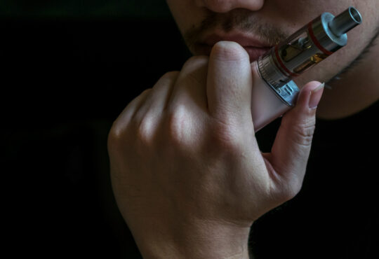Man with concealed identity smoking a controversial vaping an el