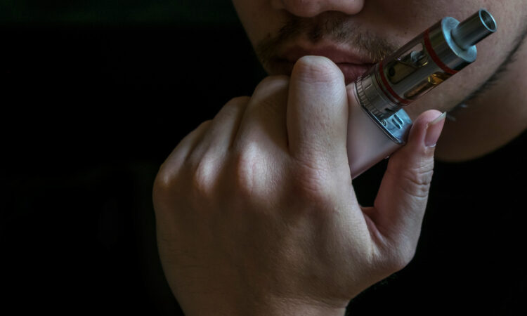 Man with concealed identity smoking a controversial vaping an el