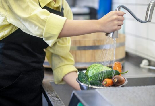 Woman in the kitchen washing vegetables before cooking