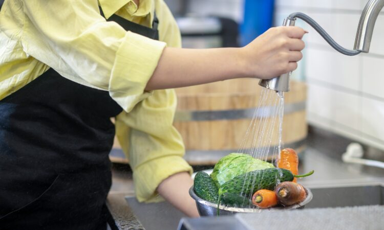 Woman in the kitchen washing vegetables before cooking