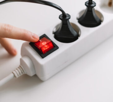 Hand turns on an electric surge protector. protection of household appliances from electrical interference. home safety
