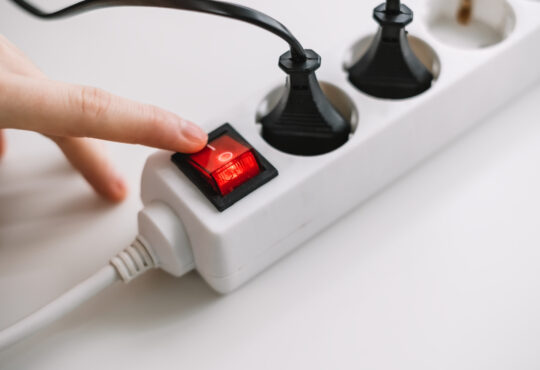 Hand turns on an electric surge protector. protection of household appliances from electrical interference. home safety