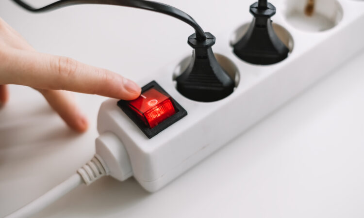 Hand turns on an electric surge protector. protection of household appliances from electrical interference. home safety